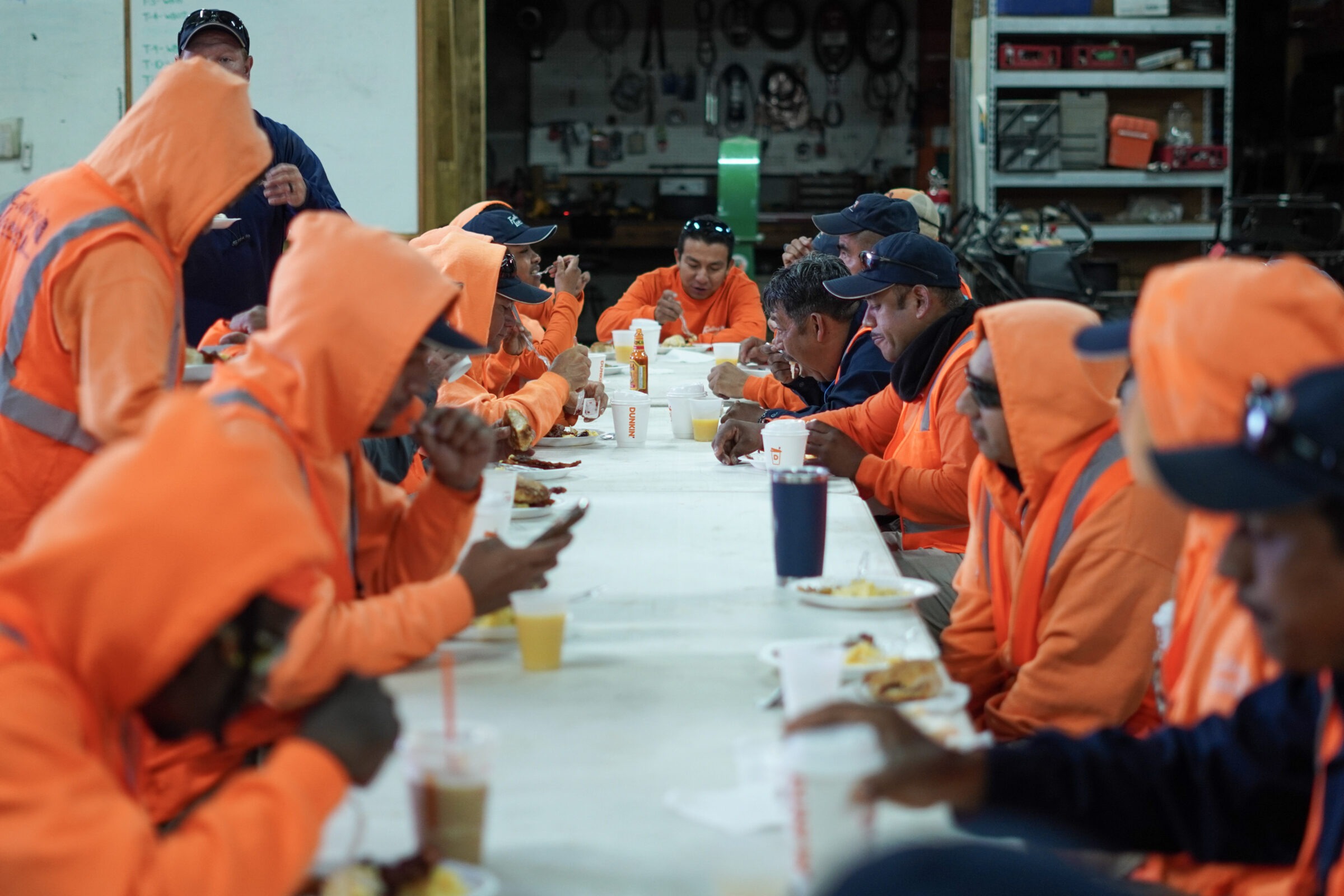 Team members in orange uniforms sit at a table enjoying a meal together.