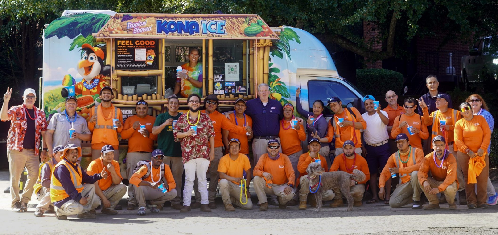 Group of employees in orange shirts waving at the camera