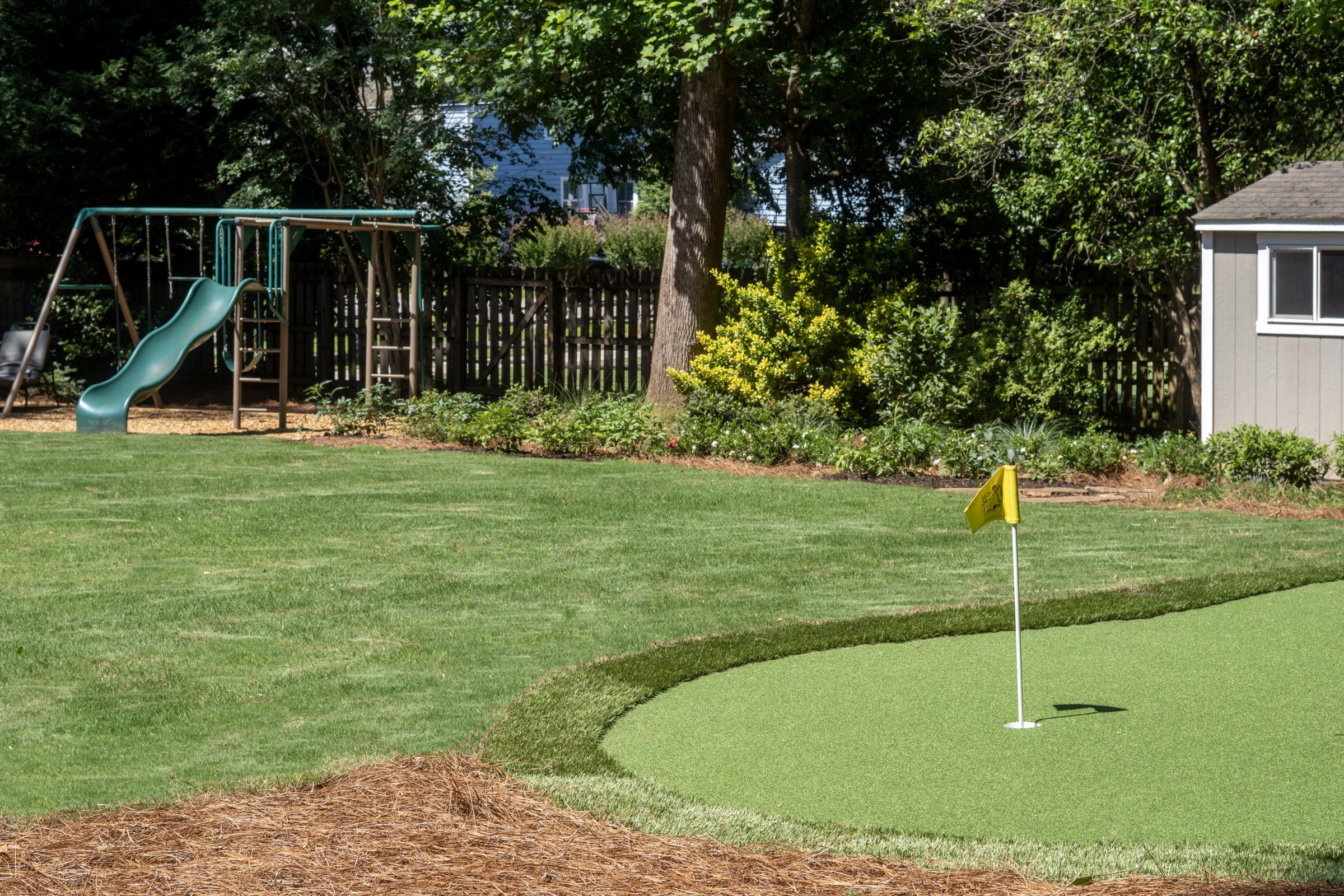 Putting green and fresh sod in front of playground and shed
